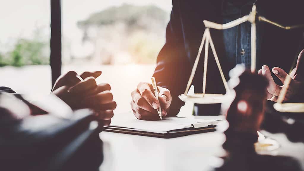 Business woman and lawyers discussing contract papers with brass scale on wooden desk in office. Law, legal services, advice, Justice concept.